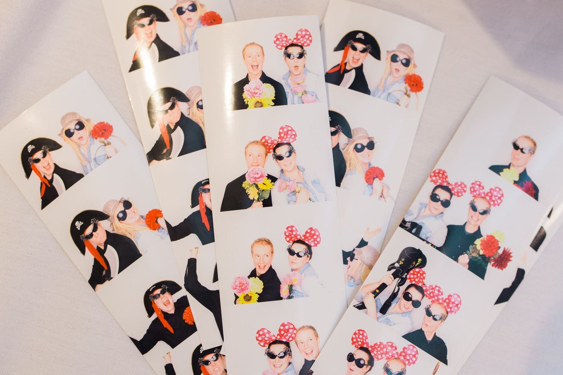 Fanned-out printed 2x6 photobooth strips, four photos each, with props